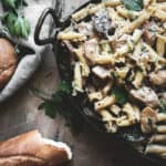 chicken marsala pasta in dish with bread, herbs, and napkin in frame
