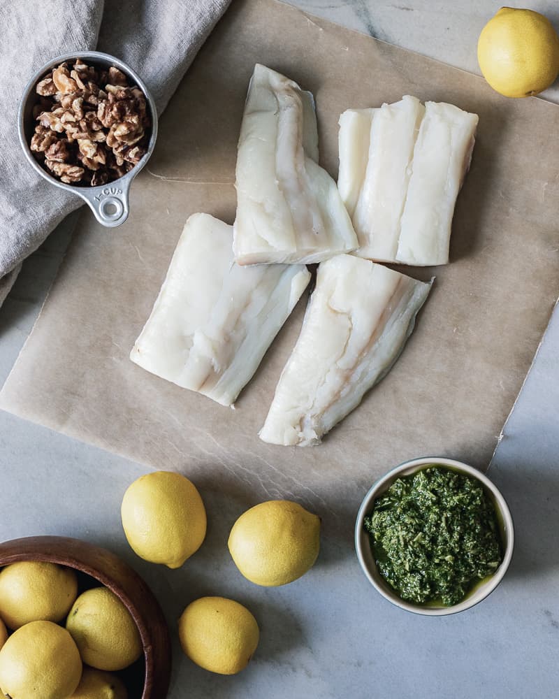 raw halibut, pesto, lemons, walnuts on marble board