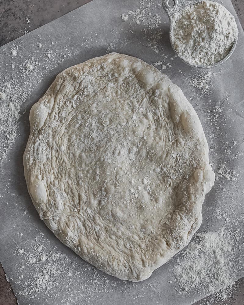 sourdough pizza crust on parchment, unbaked