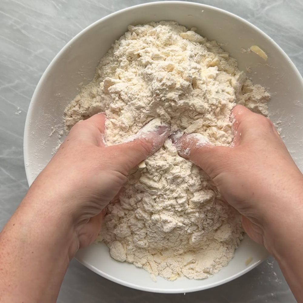 hands mixing butter into dry ingredients