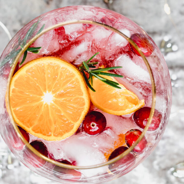 cranberry cocktail in a glass with ice and fresh clementines and cranberries