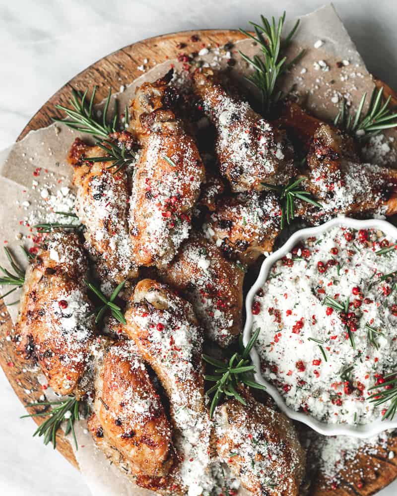 chicken wings on wooden board with parchment and rosemary