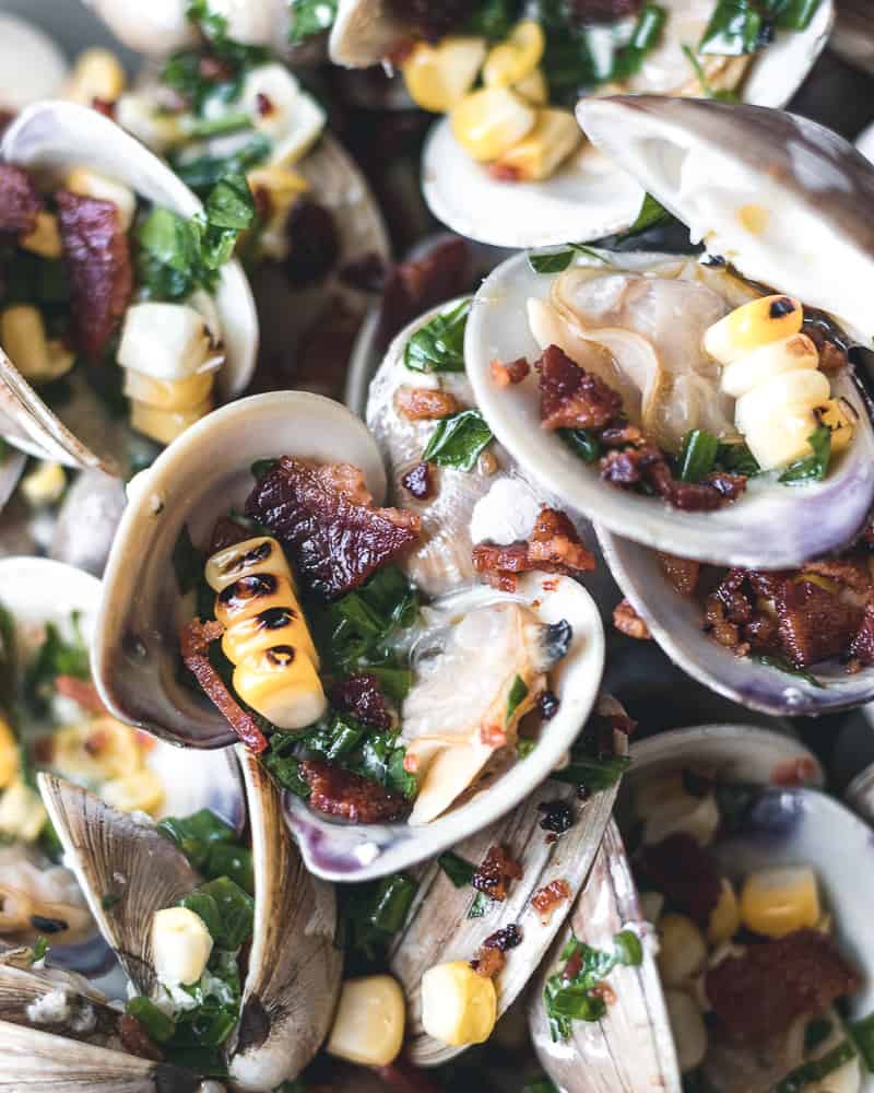 close-up of steamed clams with grilled corn and bacon