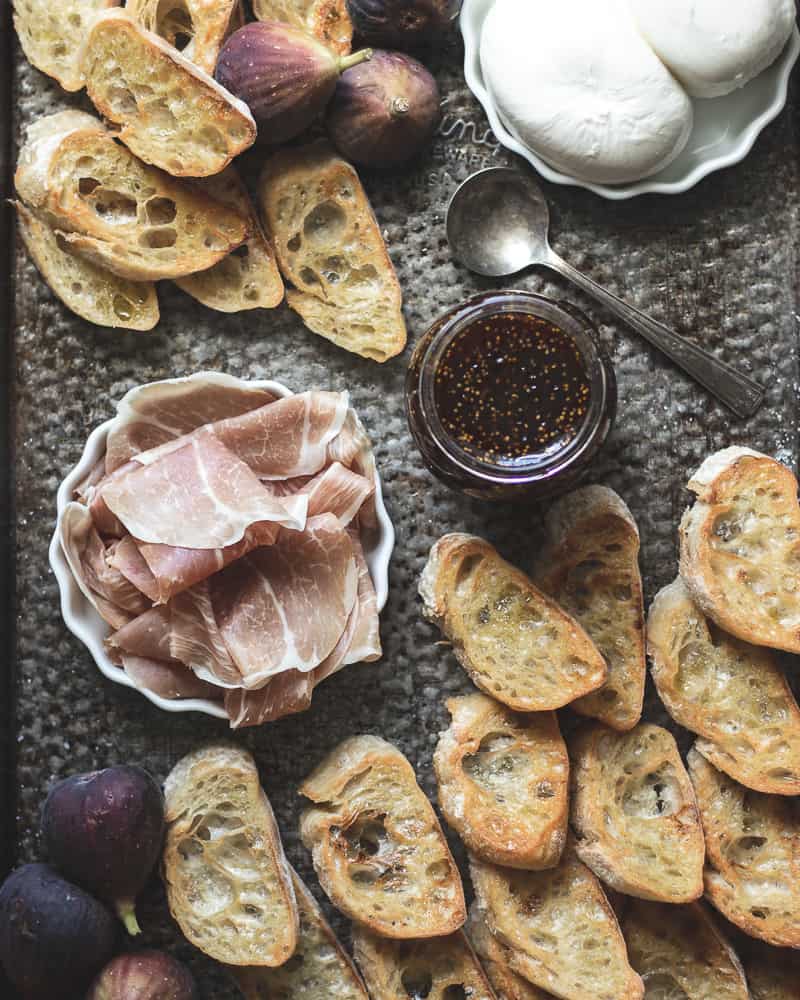 ingredients for fig, burrata, prosciutto crostini recipe on vintage baking tray