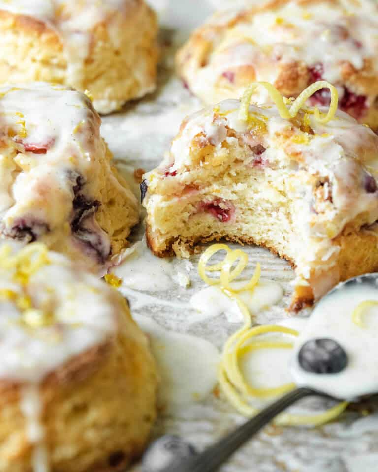 bite shot of mixed berry scone with glaze and lemon zest