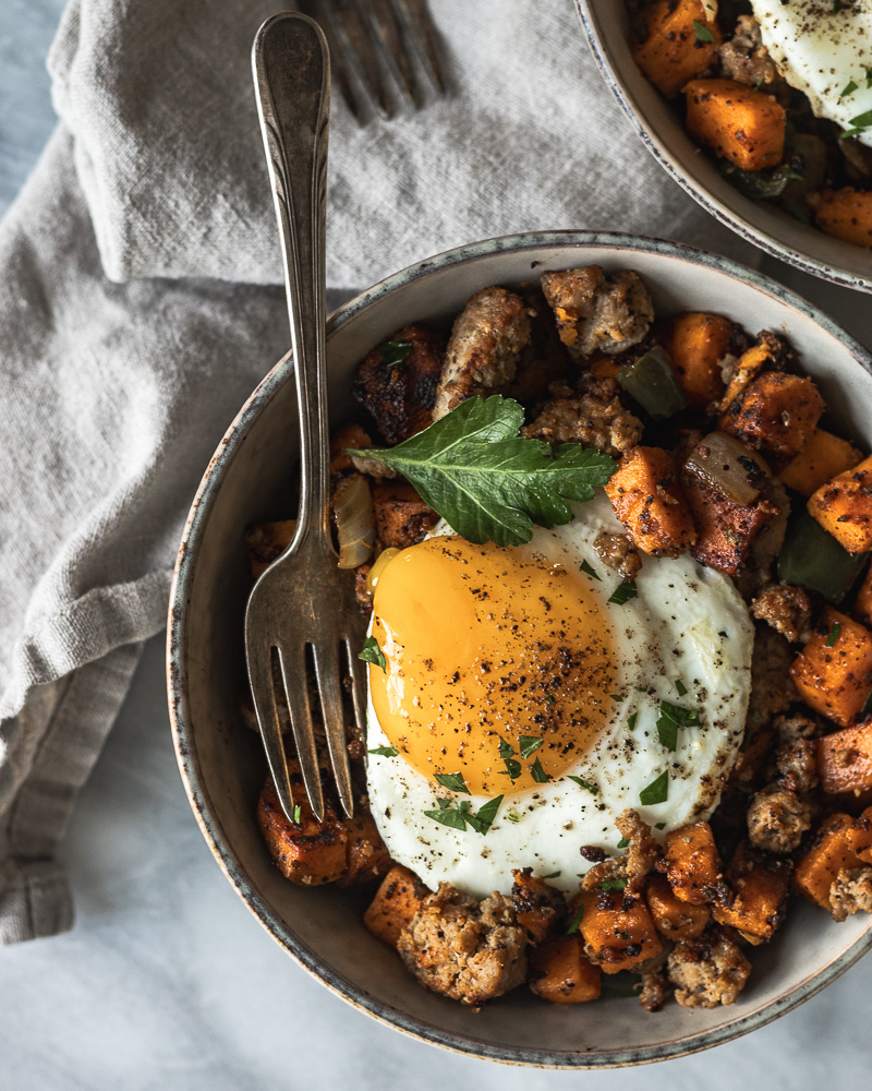 Sweet potato breakfast hash topped with sunny side up egg in a bowl 