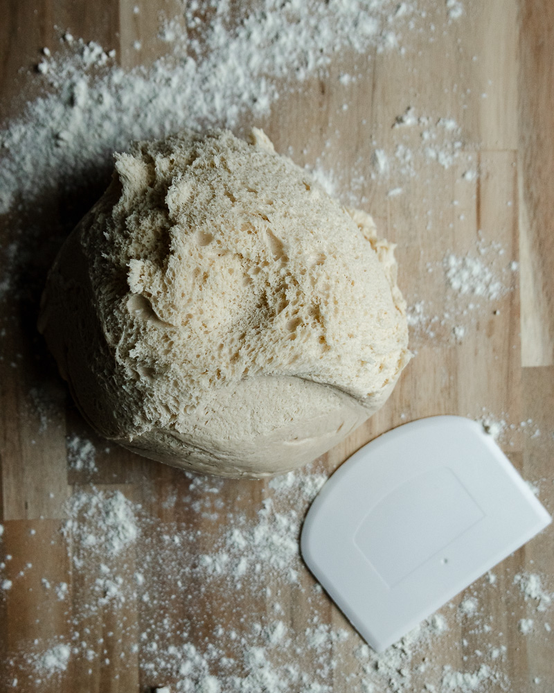 cinnamon roll dough dumped onto floured surface with white dough scraper