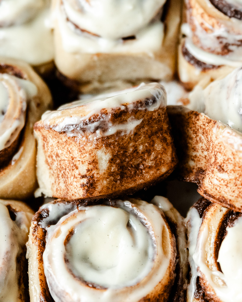 pan of sourdough cinnamon rolls with one roll unraveled and turned slightly on its side