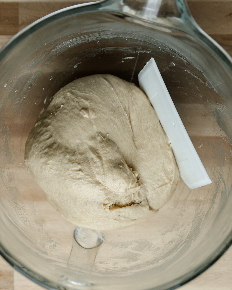 final cinnamon roll dough in mixing bowl with white dough scraper