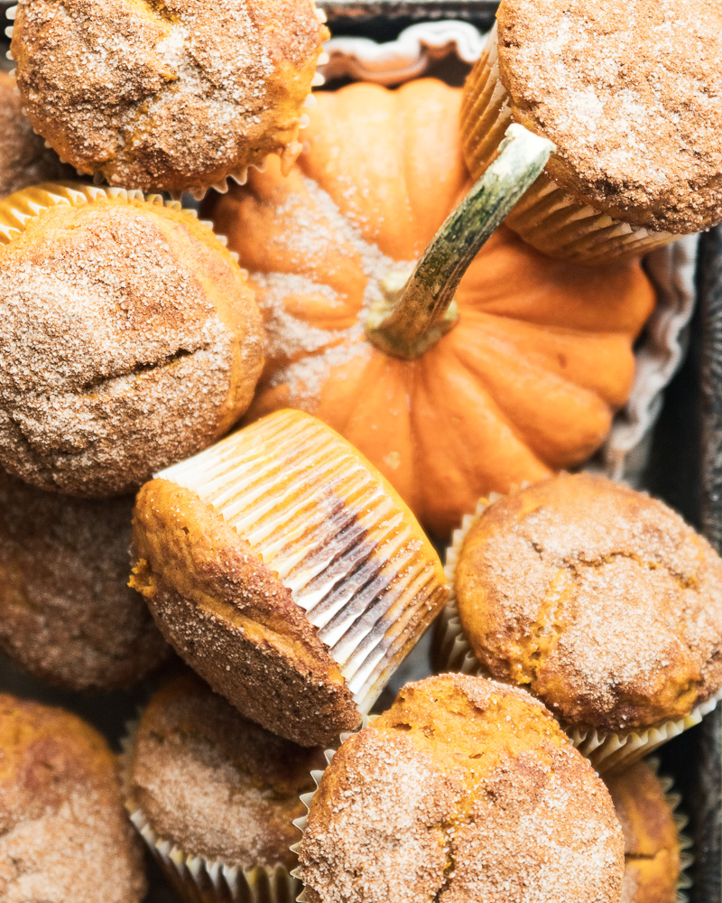 pile of muffins surrounding small decorative orange pumpkin