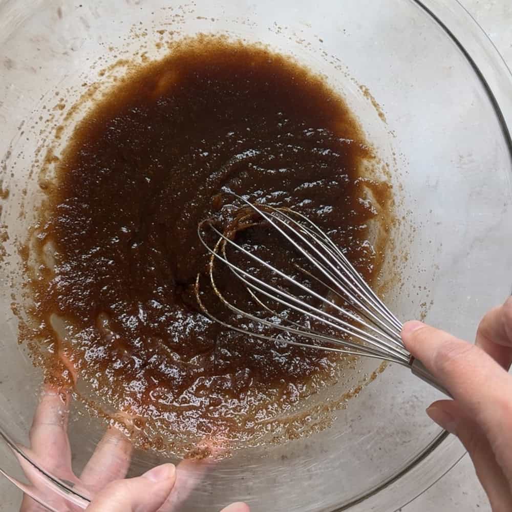 brown sugar and butter mixture being whisked in large glass bowl