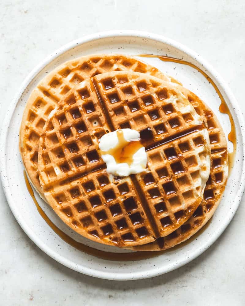 a plate with several round waffles topped with butter and syrup