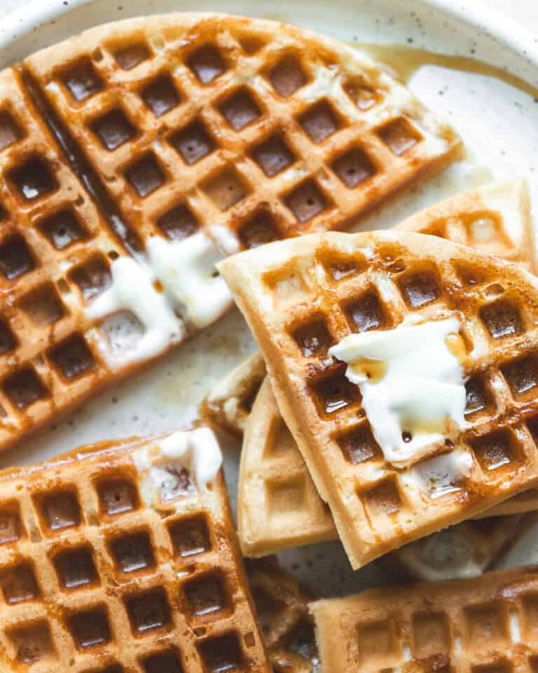 image of waffles piled on plate topped with butter and syrup