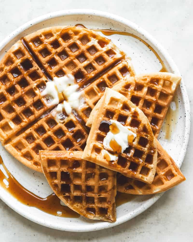 image of waffles on white plate with melted butter and syrup drizzled on top
