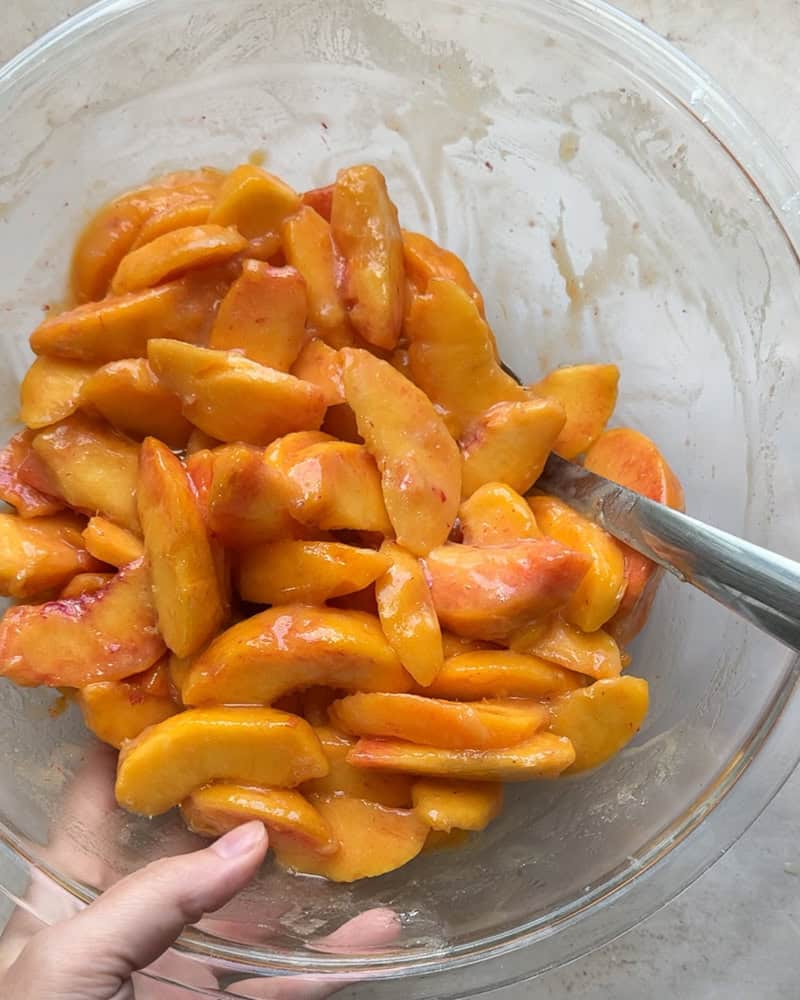 peach cobbler filling mixed together in a large glass bowl