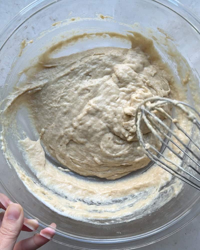 peach cobbler batter mixed together in large glass bowl with wire whisk