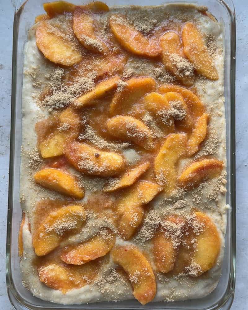 peach cobbler topped with brown sugar before baking