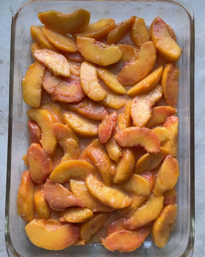 peach cobbler filling spread into glass baking dish