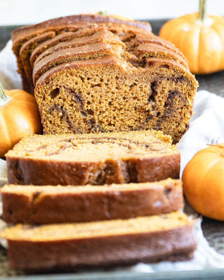 sliced pumpkin bread on tray with miniature pumpkins