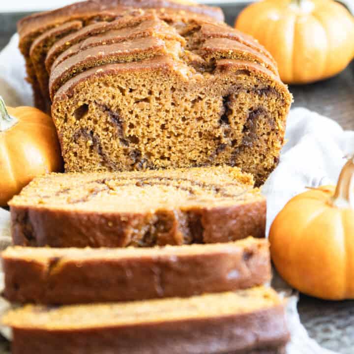sliced pumpkin bread on tray with miniature pumpkins