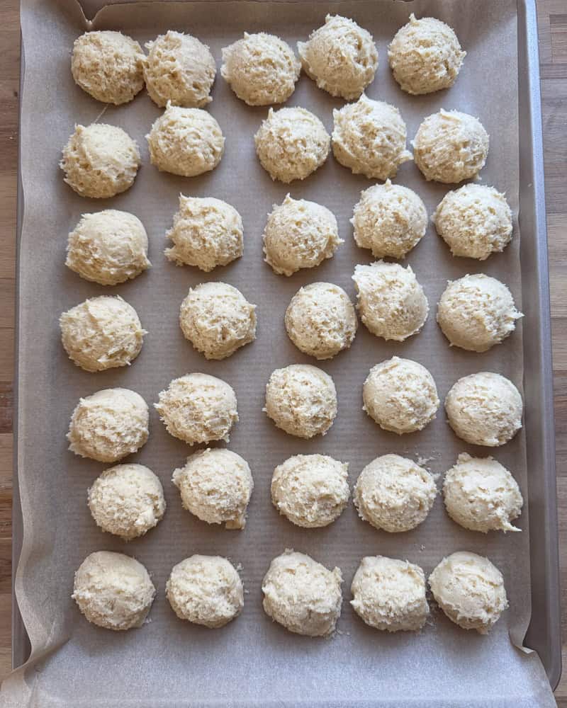 35 cookie dough balls scooped onto parchment lined baking sheet