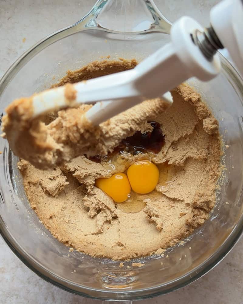 eggs and vanilla added to butter and sugar mixture in glass bowl of stand mixer