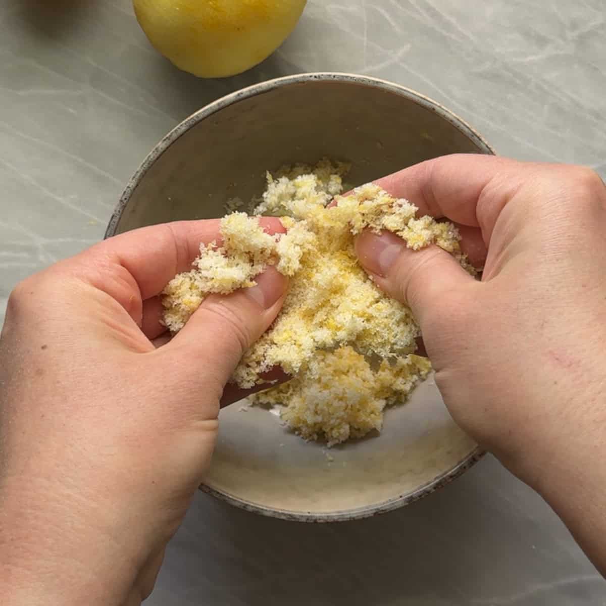fingertips rubbing together lemon zest and sugar to make lemon sugar