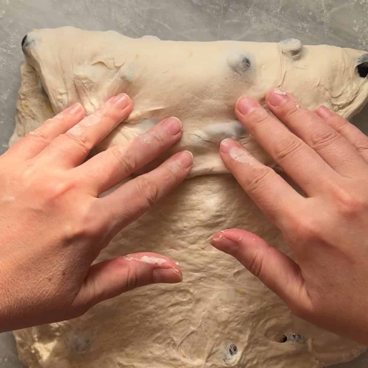 dough being folded over itself on floured surface