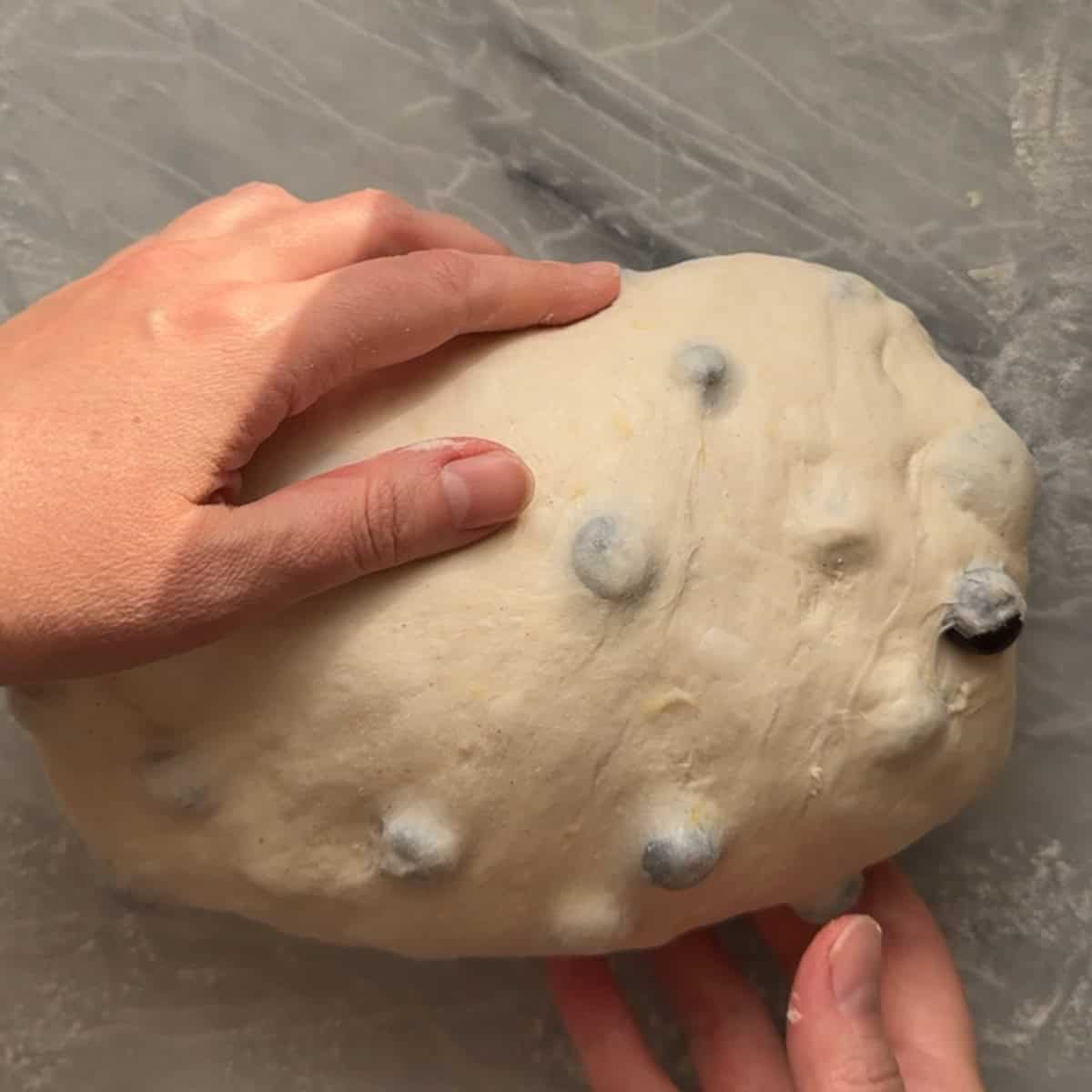 creating tension in dough by pulling gently against work surface