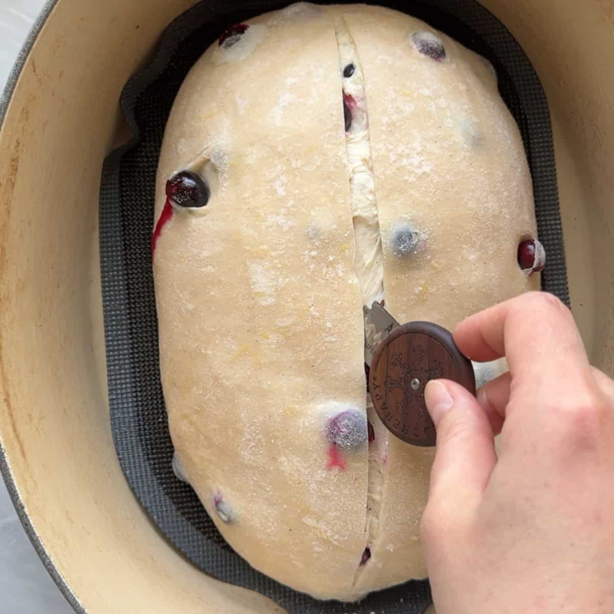 loaf being scored with a bread lame after seven minutes of baking