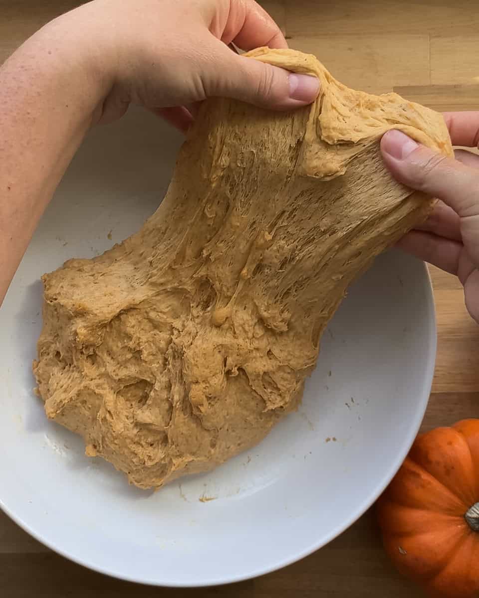 dough being pulled by hand to perform a stretch and fold