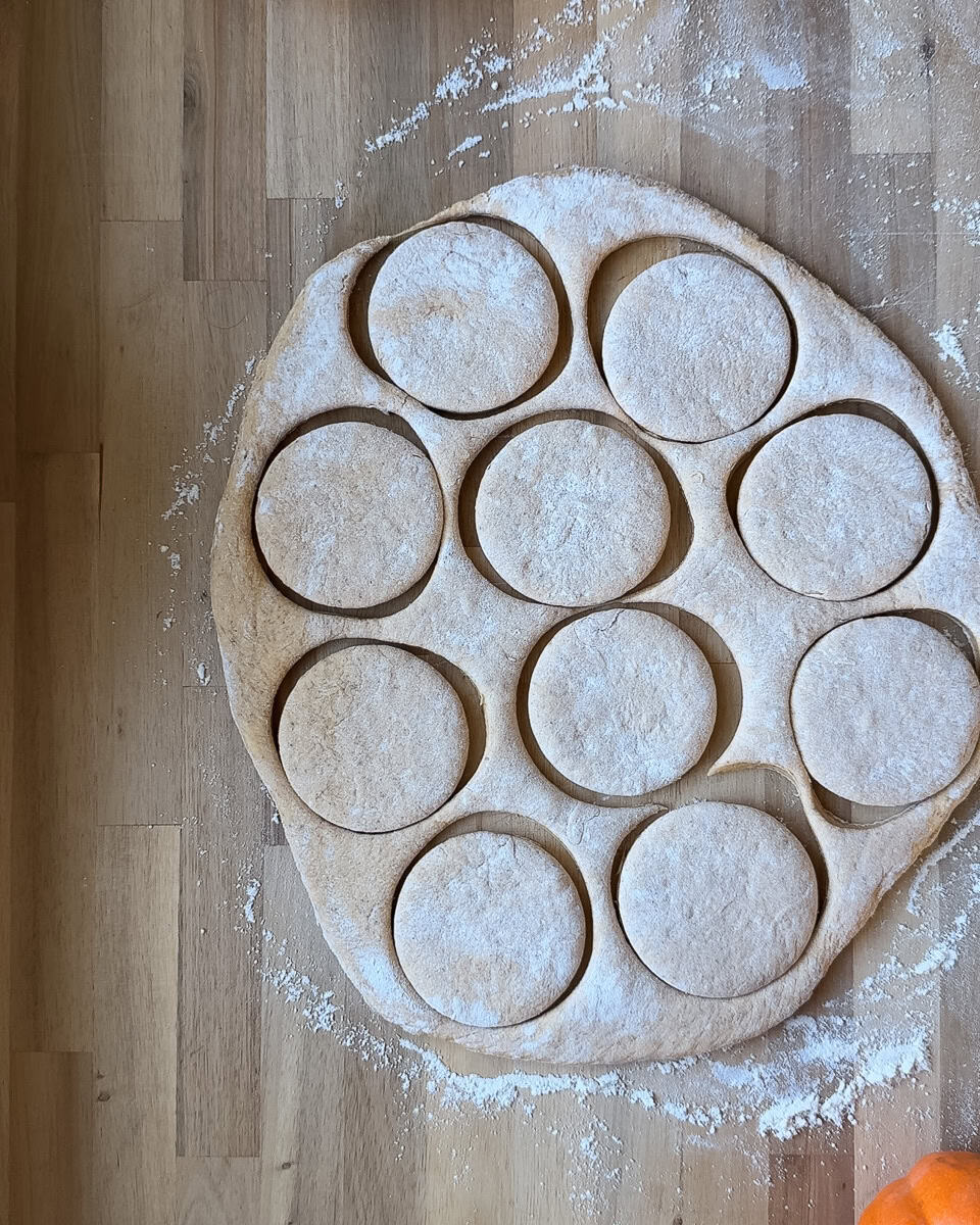 dough rolled out onto wooden surface and cut into rounds