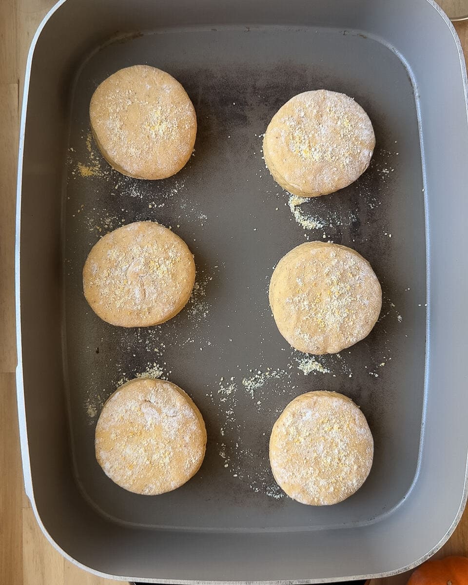 English muffin rounds being cooked in an electric griddle