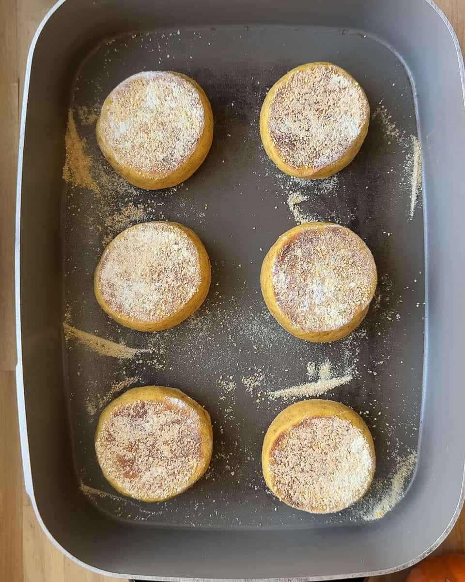 English muffins flipped and cooking on their second side in an electric griddle