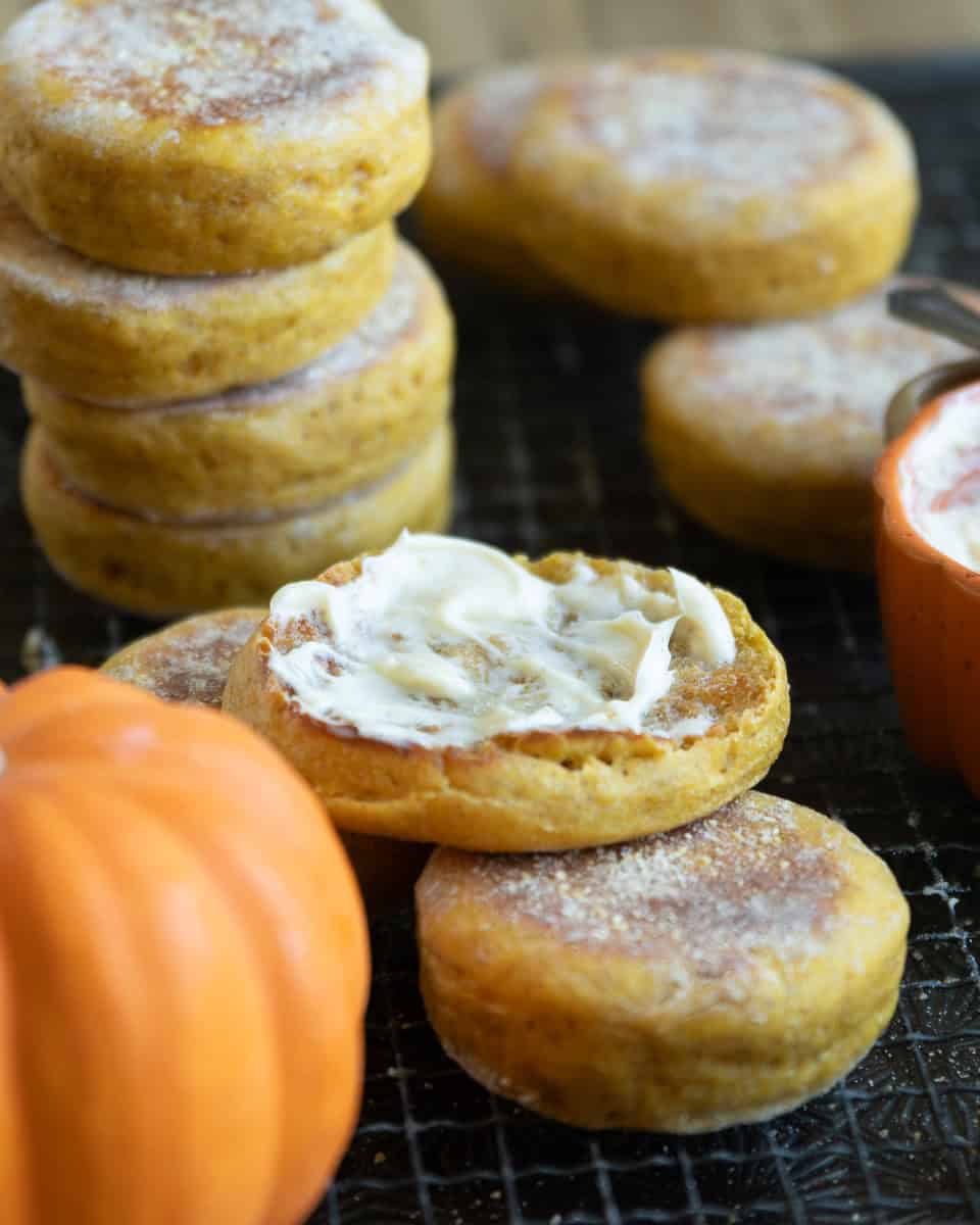 pumpkin english muffins pike on a wire rack with one split and topped with butter