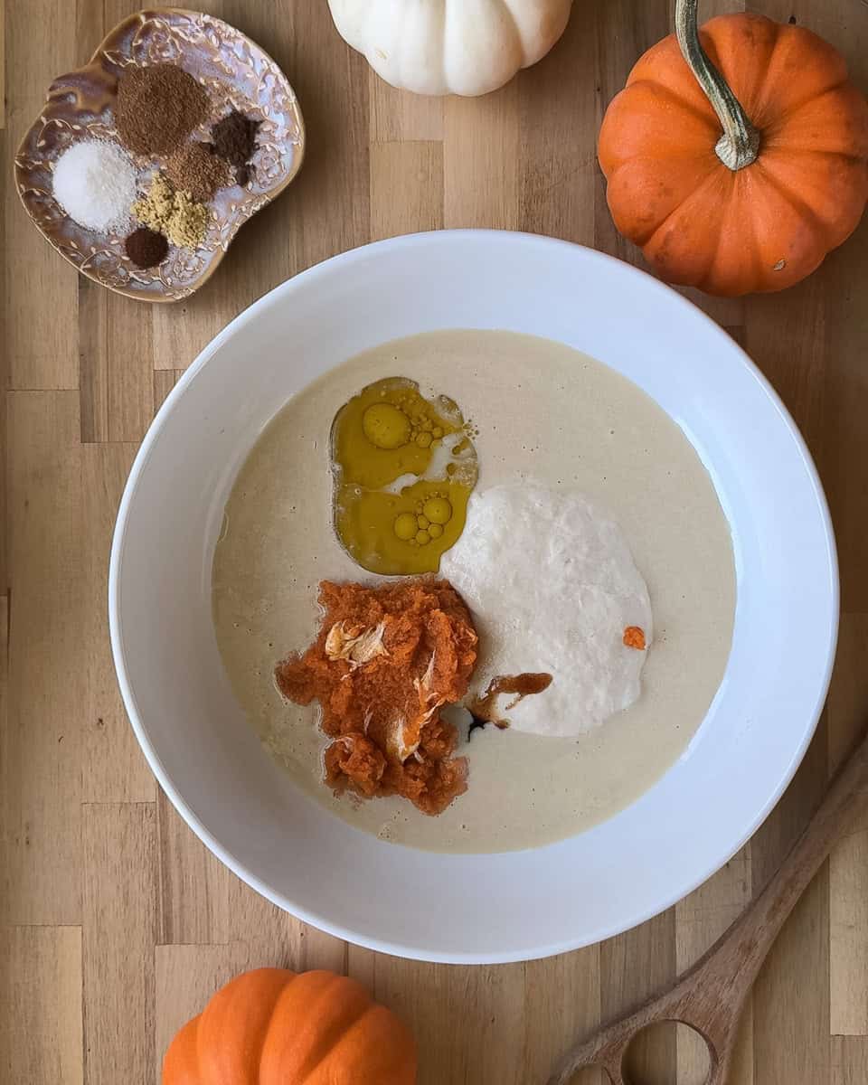 Wet ingredients including milk, pumpkin puree, vanilla, oil, and sourdough discard in a white bowl
