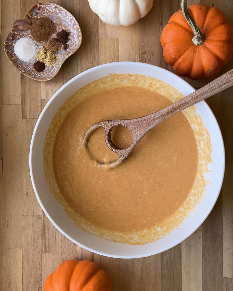Wet ingredients mixed together with wooden dough whisk in white bowl