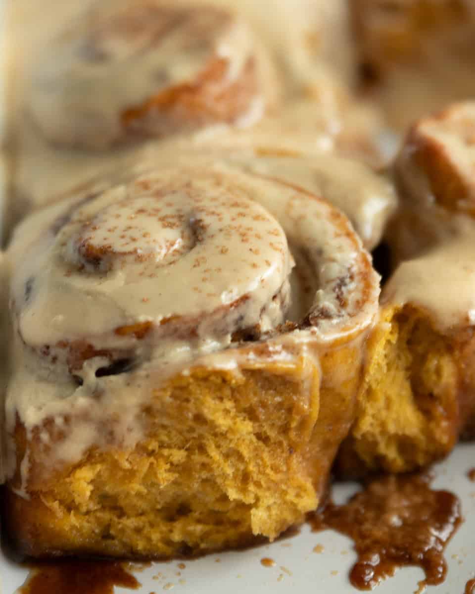 pumpkin cinnamon roll topped with frosting and pumpkin pie spice