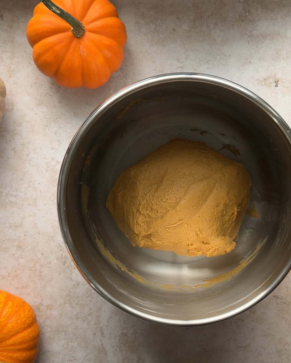 fully mixed pumpkin cinnamon roll dough in metal mixing bowl