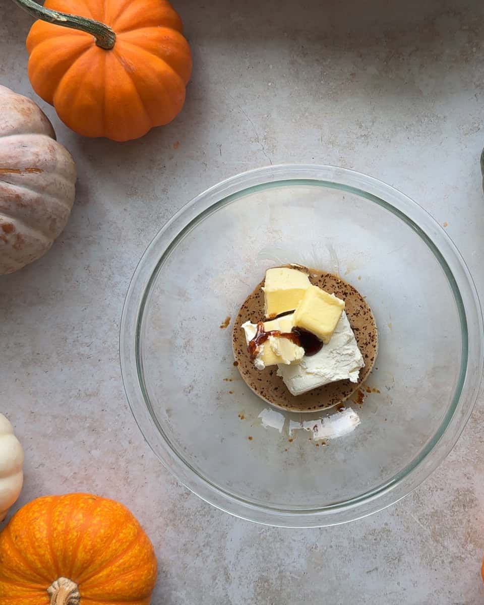cinnamon roll frosting ingredients added to milk and espresso mixture in glass bowl