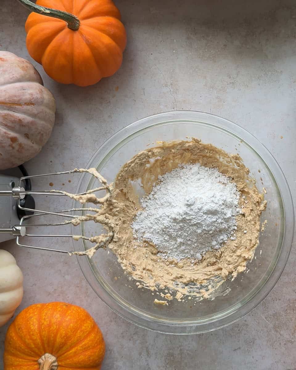 powdered sugar added to butter mixture in glass bowl