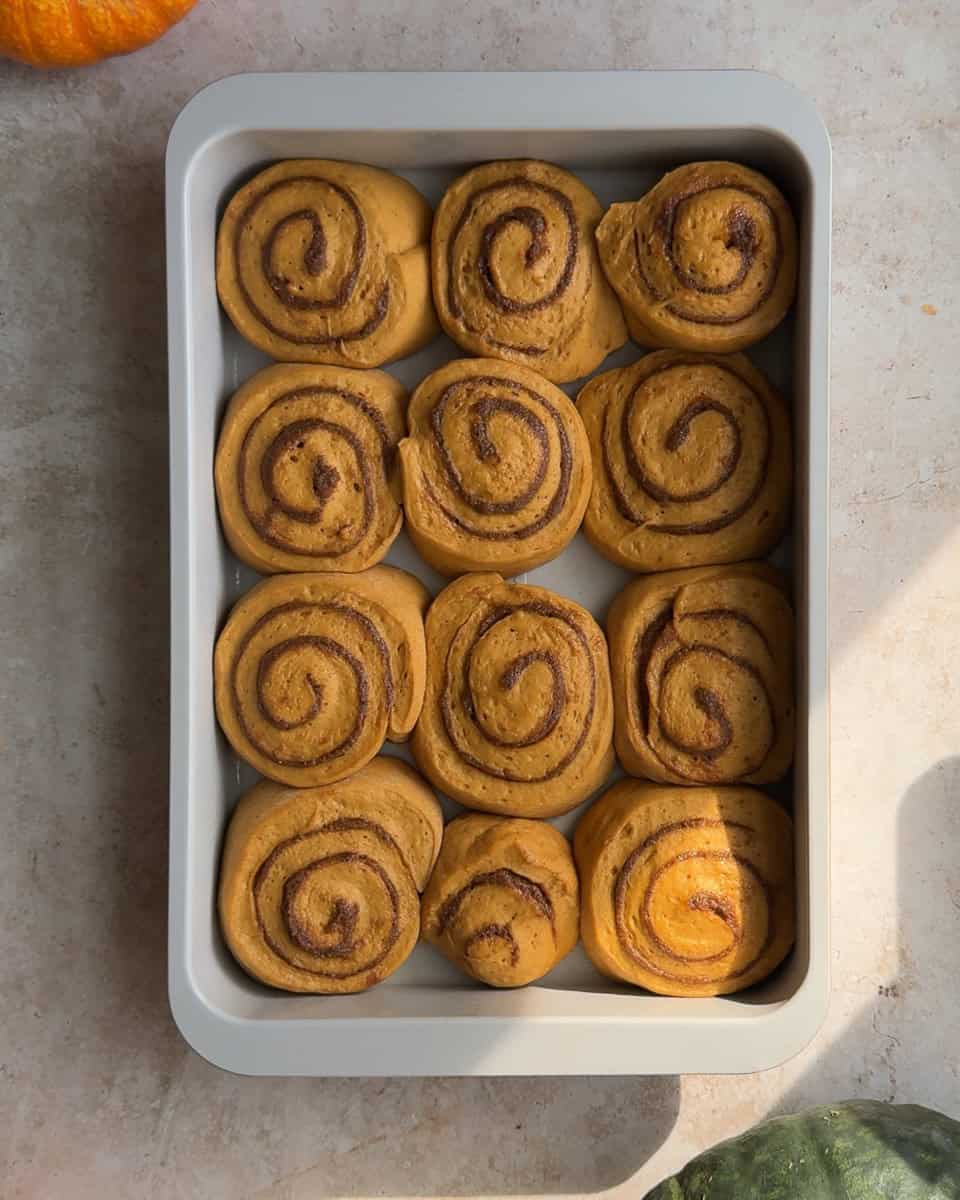 twelve cinnamon rolls in baking dish after second rise and before baking