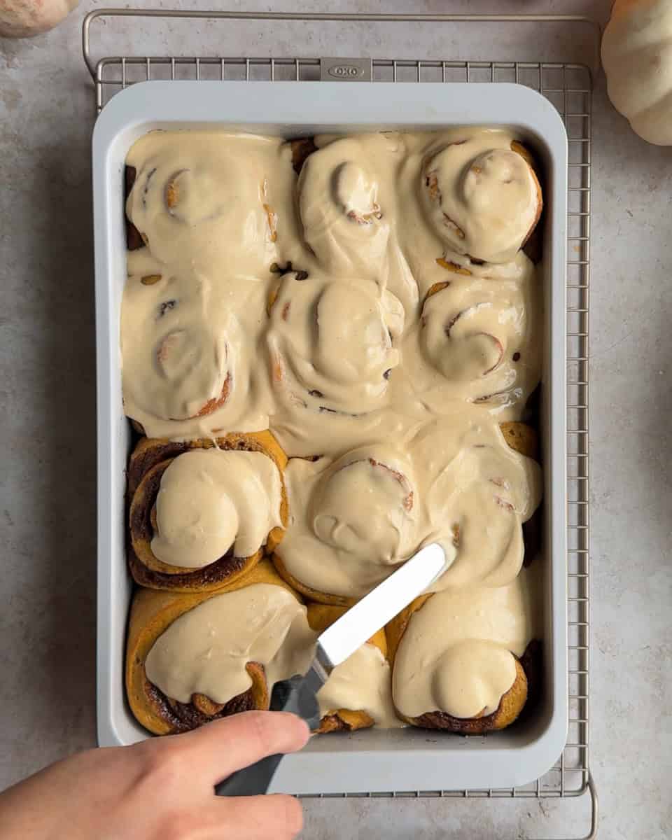 cinnamon rolls being spread with frosting